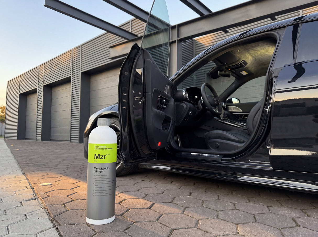 Koch-Chemie Mzr 1L Flasche neben offener Tür eines schwarzen Mercedes-AMG GT in der Warehouse-Werkstatt