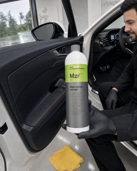 Koch-Chemie Mehrzweckreiniger Mzr in Daniels Hand am offenen Einstieg des weißen Audi RS 5, Türverkleidung tiefschwarz.