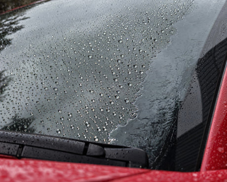 Rain repellent tested: droplets bead on sealed glass, while a water film sits on the unsealed edge