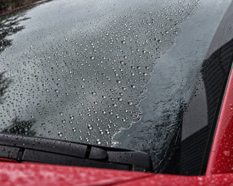 Rain repellent tested: droplets bead on sealed glass, while a water film sits on the unsealed edge